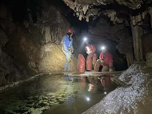 Spéléologie , groupe d'adultes devant une rivière souterraine